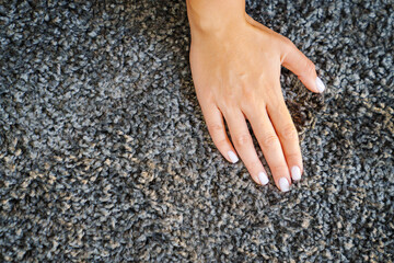 a woman's hand touching the grey Interior pile carpet 
