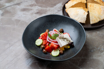 Bright and colorful Mediterranean salad featuring ripe tomatoes, olives, cucumbers, and feta cheese, accompanied by warm pita bread, elegantly presented for a delightful dining experience