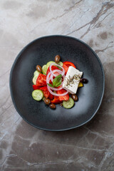 A beautifully arranged dish featuring fresh tomatoes, cucumbers, olives, onions, and feta cheese displays the essence of European culinary artistry in a cozy restaurant atmosphere