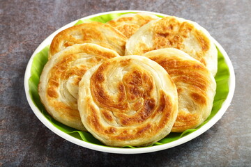 Close- up of golden brown paratha on a white plate.