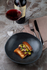 A beautifully plated dish showcases gourmet European cuisine, featuring expertly prepared meats and fresh greens. A glass of red wine adds to the sophisticated ambiance of the restaurant
