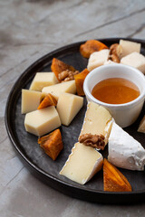 A charming dining experience unfolds with a beautifully arranged platter featuring assorted artisanal cheeses, sweet honey, and crunchy walnuts