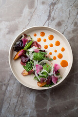 A beautifully plated dish featuring a medley of fresh leafy greens adorned with colorful vegetables and creative sauce dots, emphasizing artistry in European cuisine at a trendy restaurant