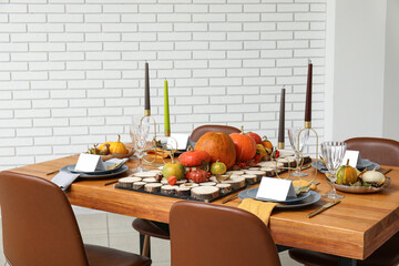 Festive table setting for Thanksgiving day with pumpkins and autumn leaves in dining room
