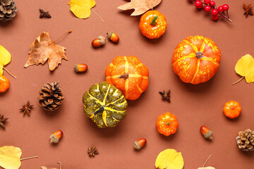 Autumn composition with ripe pumpkins, berries, spices and fallen leaves on brown background