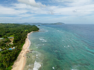 Turquoise sea water and waves. Coastline with trees and white sandy beach. Santa Fe, Tablas, Romblon. Philippines.
