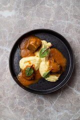 Delight in a beautifully presented dish featuring succulent meat pieces atop velvety mashed potatoes, elegantly garnished with fresh herbs, celebrating European culinary traditions