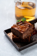 Savor a rich chocolate brownie topped with luscious caramel and a hint of mint. This delightful dessert is presented on a sleek plate, perfect for a sophisticated European dining experience