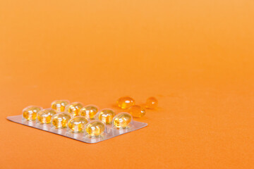 Blister package with fish oil capsules on color background. Medicine pills on a light background....