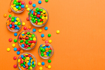 Fototapeta premium different colored round candy in bowl and jars. Top view of large variety sweets and candies with copy space