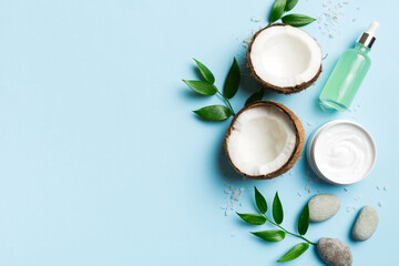 Coconut with jars of coconut oil and cosmetic cream on colored background. Top view. Free space for your text. Natural spa coconut cosmetics and organic treatment concept Coconut Spa composition