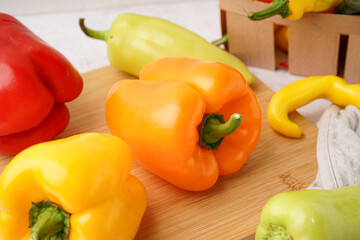Wooden board with different fresh peppers on white background