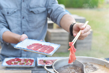 close up of chopstick Holding beef in a shabu-shabu dish