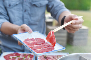 close up of chopstick Holding beef in a shabu-shabu dish
