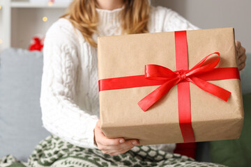 Young woman with Christmas gift box at home, closeup