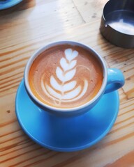 a cup of cappuccino coffee on a wooden table