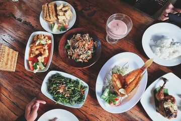 a collection of delicious food on the table, there is fried fish, vegetables, chili sauce, fruit ice, and others