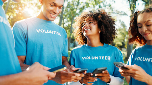 Volunteers, charity and team with phone, outdoor and communication for fundraising event or people. Happy, social responsibility and group with tech for donations, browsing and community service - Powered by Adobe