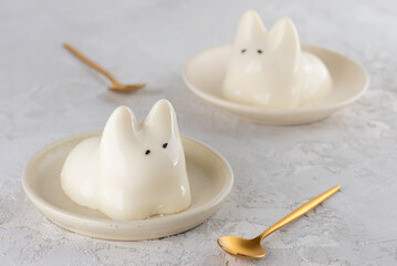 Jiggly cat dessert in a plate with golden spoon on a gray table. Dancing jelly animal mousse panna cotta. Popular Korean, Japanese pudding.