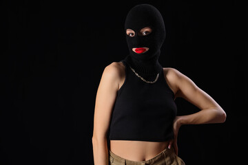 Beautiful young stylish woman in balaclava on black background