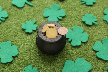 Pot with golden coins and clovers on grass. St. Patrick's Day celebration