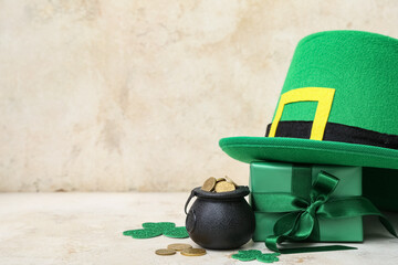 Pot with golden coins, gift box and leprechaun hat on light grunge background. St. Patrick's Day...