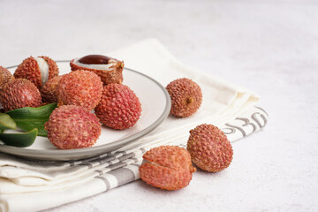 Plate with delicious litchi fruit on light background, closeup
