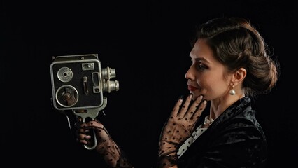 Woman actress in retro outfit with pin-up hairstyle and makeup posing at camera isolated on black...