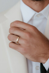 Groom showing golden wedding ring on finger while wearing elegant suit