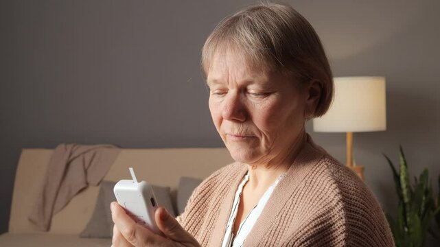 A senior adult demonstrates how to use a glucometer in a cozy living room. The process highlights the importance of self-monitoring blood sugar levels for health management