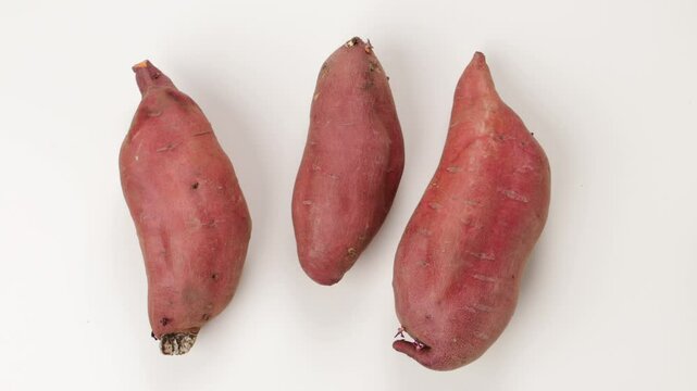 top view of uncooked sweet potatoes on white background
