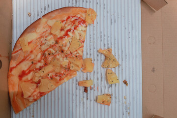 Pizza slice in the in delivery box.Thai style pizza with pineapple as an ingredient.