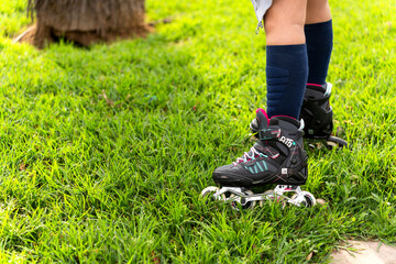 Girl wearing inline skates standing on green grass in a park