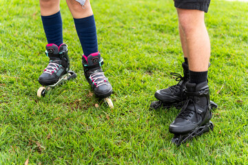 Fototapeta premium Couple wearing inline skates standing on grass field