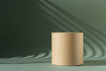 Brown round corrugated cardboard podium on green background with Light on wall. The concept mockup