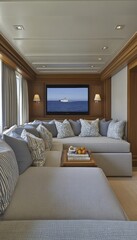 Relaxing lounge area with a large screen showing a yacht at sea, plush seating and coffee table with books.