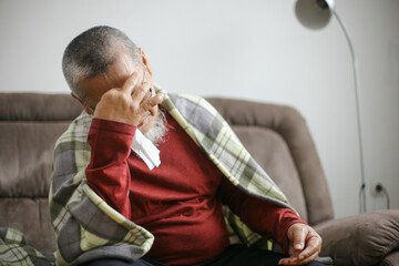 Obraz premium Sick Asian Old Man In Blanket Having Headache Or Fever With Tissue On Nose