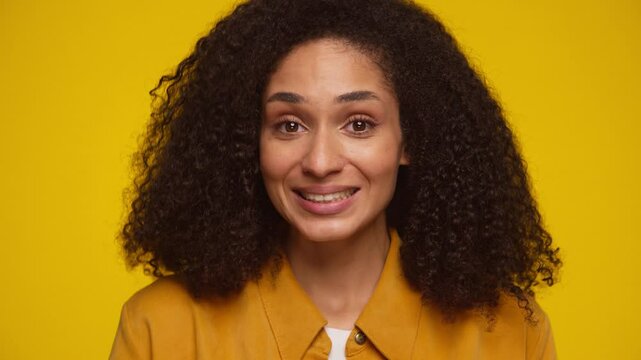 Woman making awkward smile on yellow background