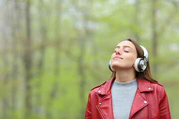Happy woman in nature meditating with headphone