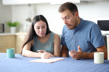 Perplexed interracial roommates checking document at home