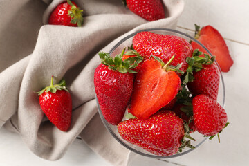 Glass bowl with sweet fresh strawberries on white wooden background