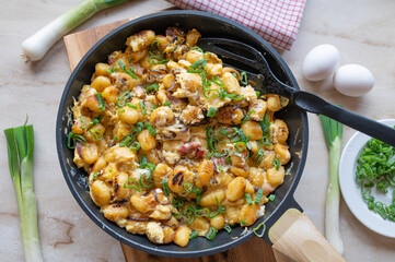 Pan fried gnocchi with bacon, red onions and eggs in a skillet