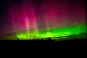A stunning display of the Northern Lights with green and pink hues illuminating the night sky filled with stars.