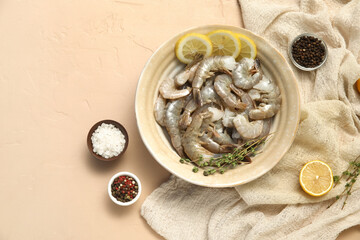 Bowl with fresh raw shrimps and lemon on beige background