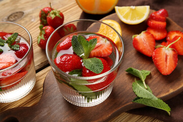 Glasses of infused water with strawberries and mint on wooden background