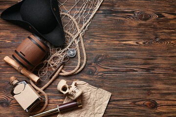 Pirate hat with rum, skull, map and net on wooden background