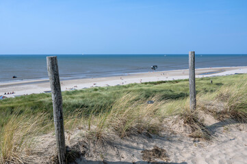Dunes with beach grass and a barbed wire fence on the North Sea coast, with a view of the sandy...