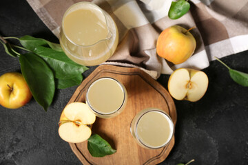 Glasses and jug of fresh apple kvass on black background