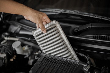 Man hand holding dirty and dusty air filter to check or replace in car at garage concept of...