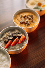 4 types of porridge in white bowls on a wooden background, oatmeal, corn, millet and rice